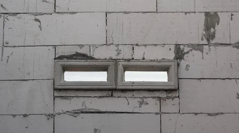 Two rectangular vents with mesh screens set into a white concrete block wal.. Foto stock