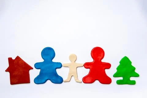 Two red and blue plasticine men, as parents, hold the hand of a white plastic Stock Photos