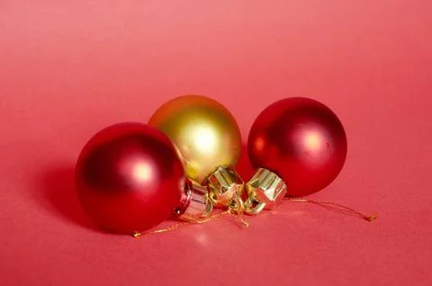 Two red and one gold Christmas ball lying on a red background Stock Photos