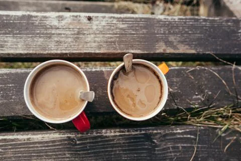 Two red and orange coffee cups on table outdoor, closeup Stock Photos
