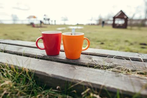 Two red and orange coffee cups on table outdoor, closeup Stock Photos