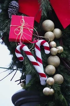 Two red and white candy canes, a wrapped red present and some golden bauble.. Stock Photos