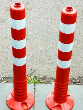 Two red and white restrictive posts stand on the sidewalk Foto stock