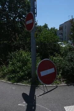 Two red and white stop signs in front of trees on a sreet in france Stock Photos