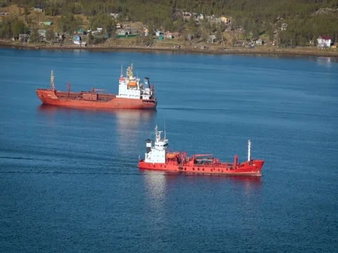 Two Red and White Vessels of Similar Size Are on the Water. Blue Water, Houses Video stock 71565000