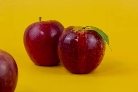 Two red apples isolated on yellow background. Two fresh apples fruits used fo Stock Photos