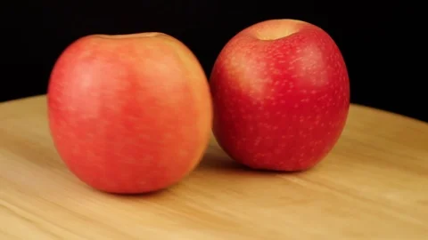 Two red apples rotate 360 degrees on a wooden stand Stock Footage 119176839