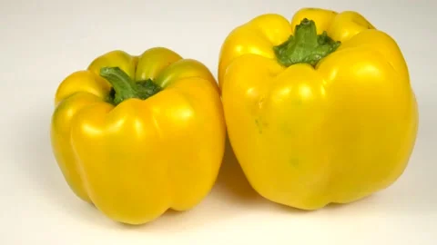 Two red bell peppers of different shapes are on a white board Stock Footage 319401325