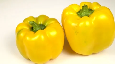 Two red bell peppers of different shapes are on a white board, rotation Stock Footage 319401342