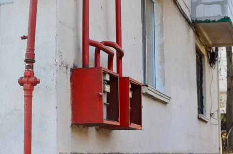 Two red boxes on a wall next to a pipe. Stock Photos