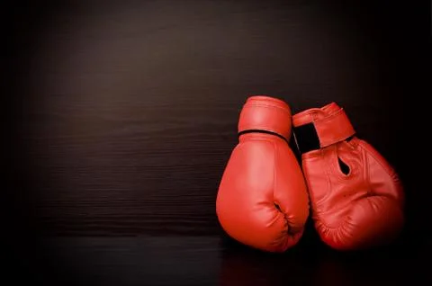 Two red boxing gloves on the side of the frame on a black background, empty s 스톡 사진