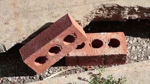 Two red bricks with three circles holes in each next to curb with one leaning Stock-Footage 249098767