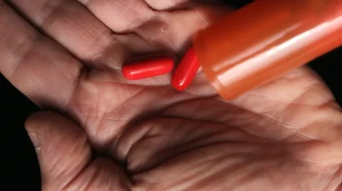 Two red capsules in hand Видео 12114678