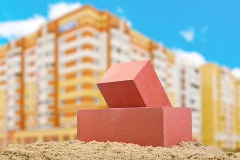 Two red ceramic bricks on the sand at the building background Stock Photos