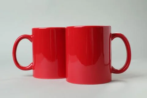 Two red ceramic mugs on light grey background Foto stock