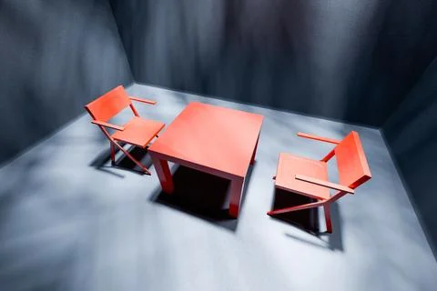 Two red chairs and table in spotlight in empty dark interrogation room Stock Photos