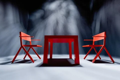 Two red chairs and table in spotlight in empty dark interrogation room Stock Photos
