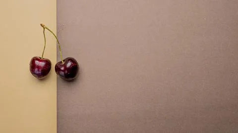 Two red cherries on a bicolor brown background Stock Photos