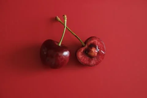 Two red cherries on red background Stock Photos