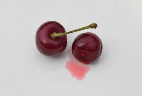 Two red cherries on a white table. Diet food concept. Photos