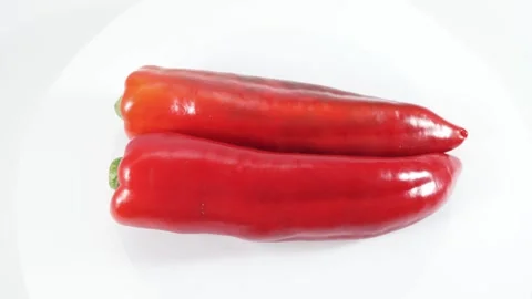 Two red chili peppers rotating vertically in a minimalist studio setup. Stock Footage 325527872