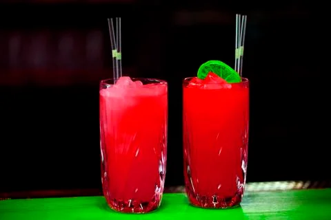 Two red cocktail drinks on black background on green table. Stock Photos