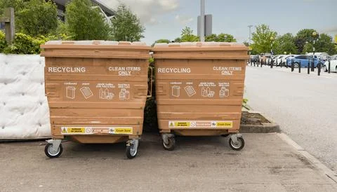 Two Red Commercial Recycle bins in front of plain grey wall Stock Photos