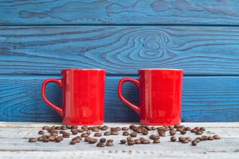 Two red cups and coffee beans on a background of blue boards Stock Photos