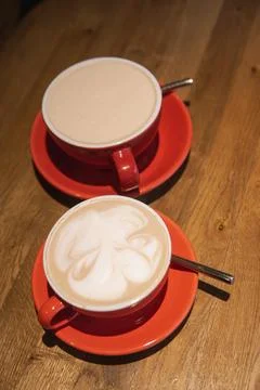 Two red cups filled with coffee served on wooden table Stock Photos