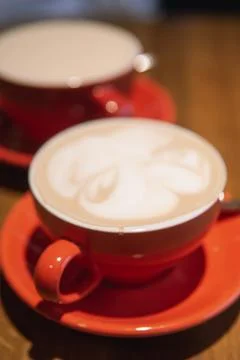 Two red cups filled with coffee served on wooden table Stock Photos