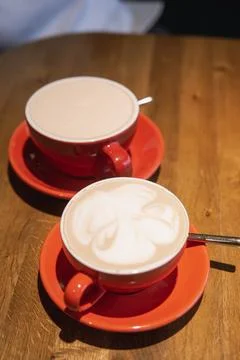 Two red cups filled with coffee served on wooden table Stock Photos