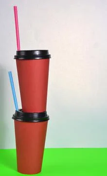 Two red cups stand on top of each other against a white background. Stock Photos