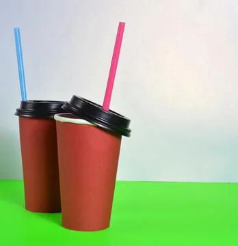 Two red cups with straws stand next to each other on a white background Stock Photos