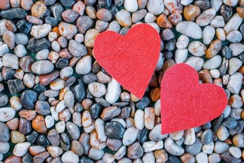 Two red decorative hearts and gray sea pebbles. Stock Photos