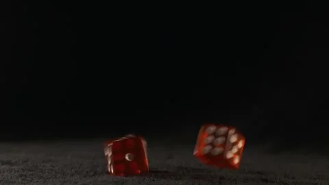 Two red dice thrown on a black casino table they are slowly turning in the .. Stock Footage 242597784