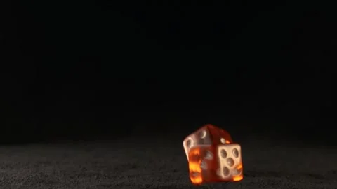 Two red dice thrown on a black casino table they are slowly turning in the .. Stock Footage 242598091