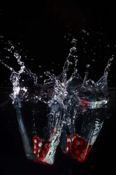Two red dices being dropped in water Stock Photos