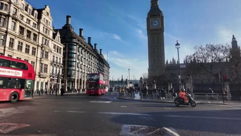 Two red double decker buses travel on a street near the Houses of Parliament Vídeos de archivo 328353204