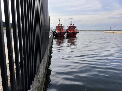 Two red fire boats are moored at pier in  river port Stock Photos