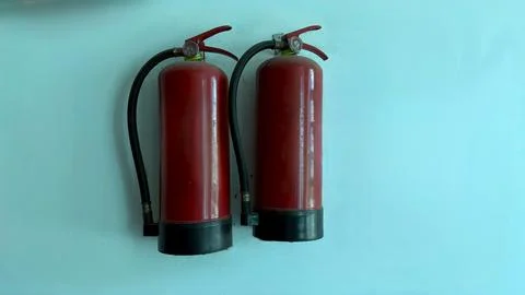 Two red fire extinguishers are mounted on the blue wall inside the building Foto stock