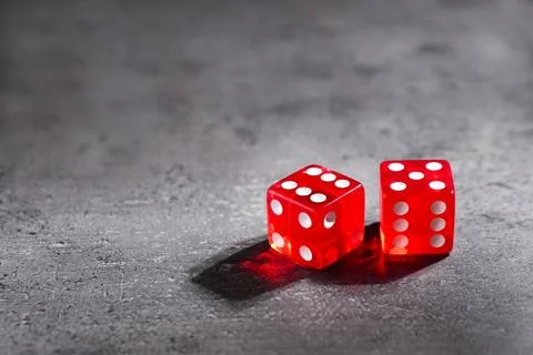 Two red game dices on grey textured table. Space for text Stock Photos