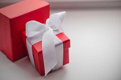 Two red gift boxes, one of which is tied with a white ribbon Stock Photos
