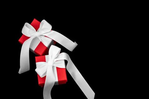 Two red gift boxes with white bows on a black background. 스톡 사진