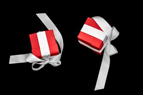 Two red gift boxes with white bows levitate on a black background. Фото