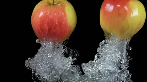 Two red-green apples are jumping from the water with splashes Stock Footage 213229988