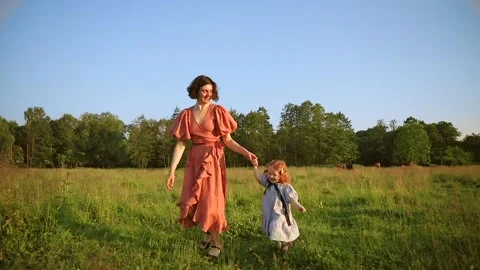 Two red-haired sisters and their mother run across the field Stock Footage 218299728