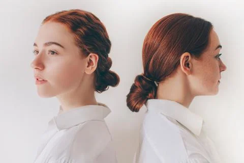 Two red-haired sisters stand isolated on a white background in shirts. Women Stock Photos
