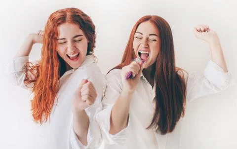 Two red-haired sisters stand isolated on a white background in spacious Stock Photos