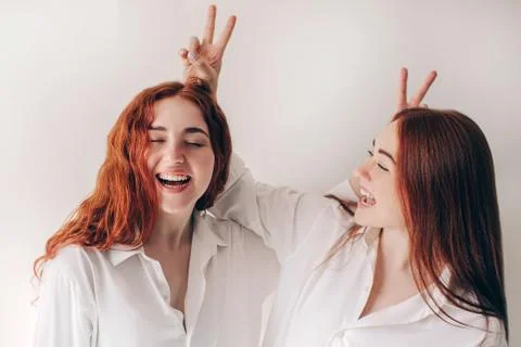Two red-haired sisters stand isolated on a white background in spacious Stock Photos