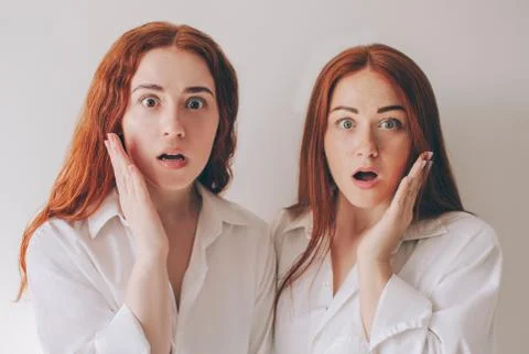 Two red-haired sisters stand isolated on a white background in spacious Stock Photos